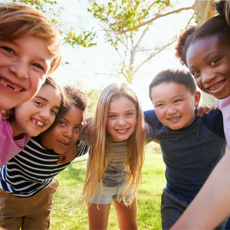 A group of children of various nationalities hugging and smiling at the camera