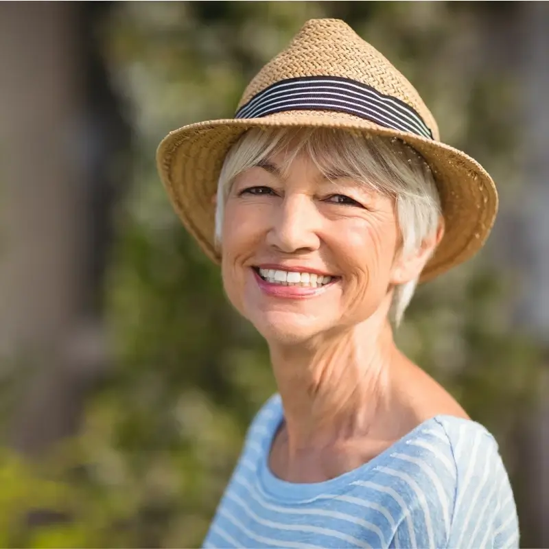 A senior woman with a straw hat happy and serene thanks to sophrology