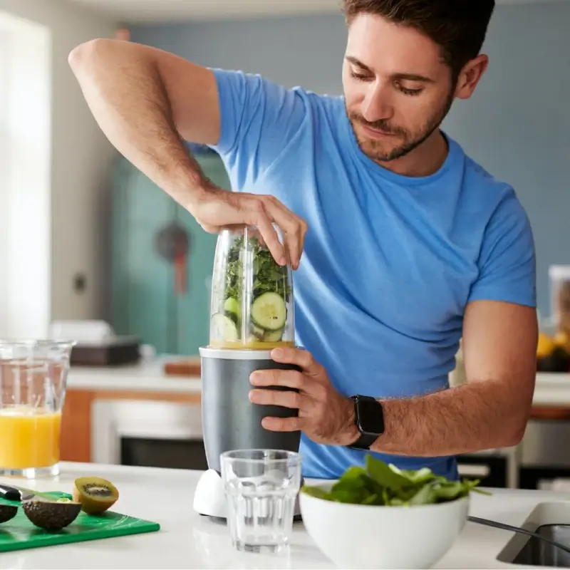 Man making healthy juice drink with fresh ingredients in electric juicer