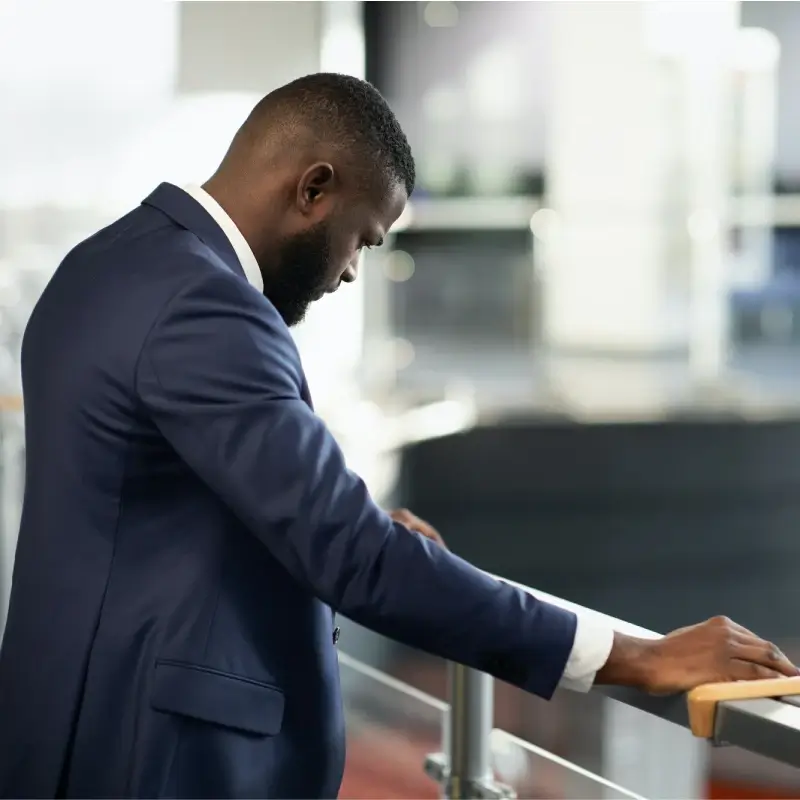 A stressed businessman with his hands on the railing of a building