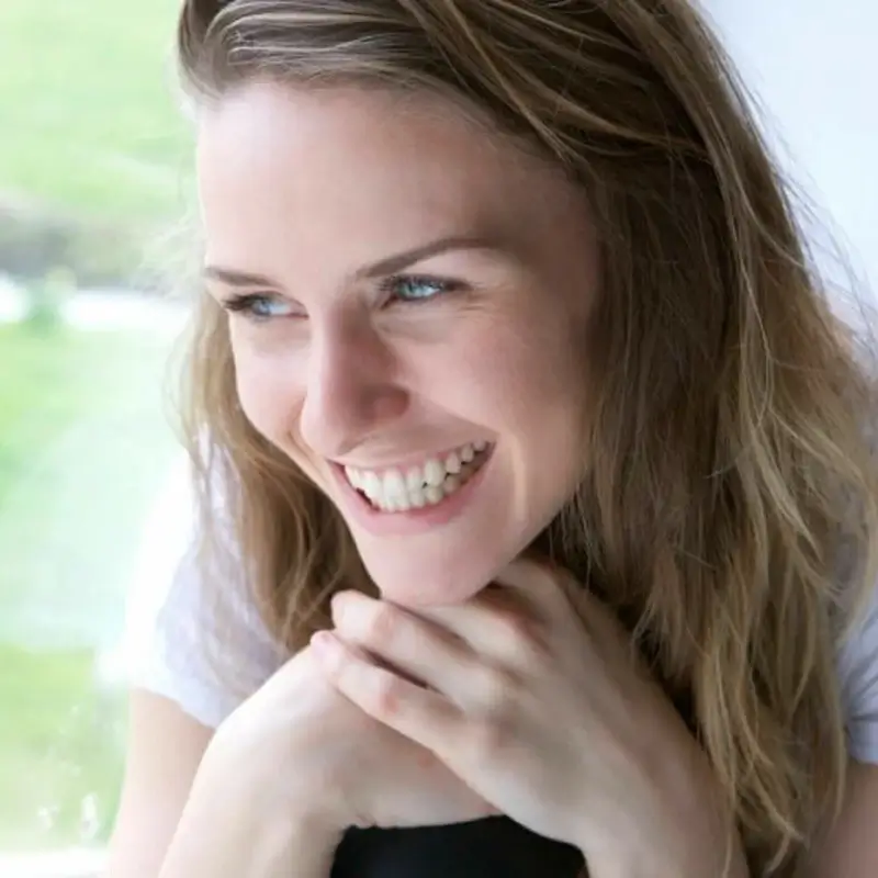 A blonde woman with light eyes smiling positive effects of Caycedian Sophrology