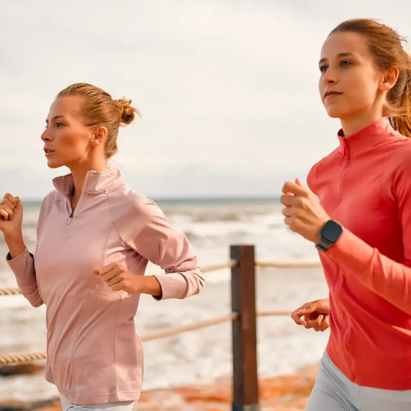 Two female athletes running with the sea in the background